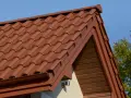Brązowa, lekka konstrukcja dachu z dachówki ceramicznej, z widocznym okapem i drewnianą podbitką.