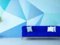 Nowoczesny salon z niebieską kanapą i geometrycznymi wzorami na ścianie malowanymi farbą.