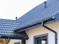 Szary dach z dachówki i rynny. Zastanawiasz się, ile farby na 100m2 dachu?