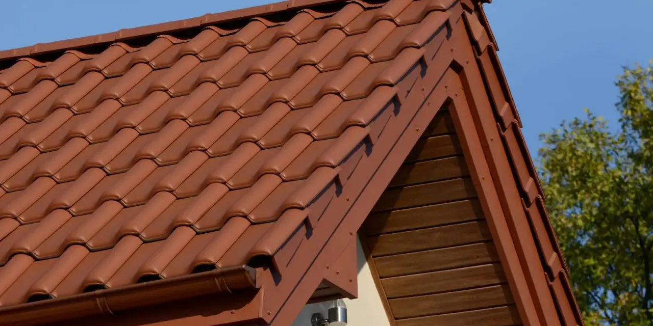 Brązowa, lekka konstrukcja dachu z dachówki ceramicznej, z widocznym okapem i drewnianą podbitką.