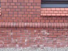 Elewacja z elementami cegły, z ozdobnym gzymsem i dachówkami.