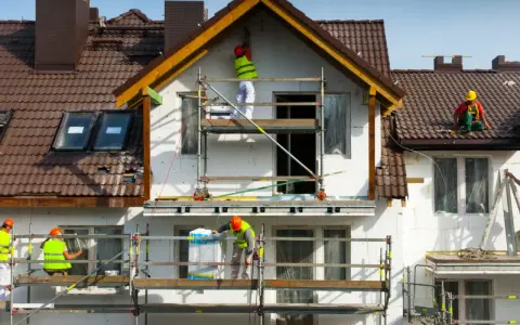 Pracownicy na rusztowaniach ocieplają dom. Może to być próba uniknięcia kary za samowolę budowlaną.