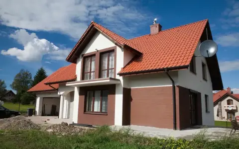 Jaki kolor elewacji do czerwonego dachu? Biała elewacja z brązowymi akcentami, jak na tym domu, wygląda stylowo.