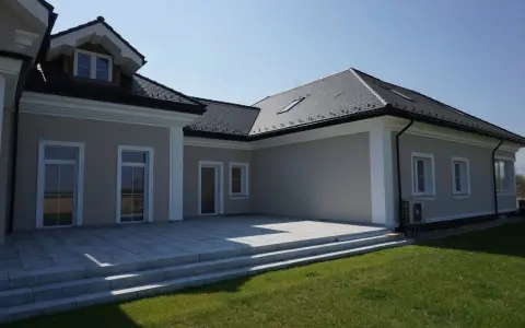 Nowoczesny dom z tarasem i trawnikiem. Elegancki gzyms podkreśla architekturę budynku.