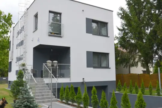 Nowoczesny dom z biało antracytową elewacją, schodami i metalową klatką schodową.