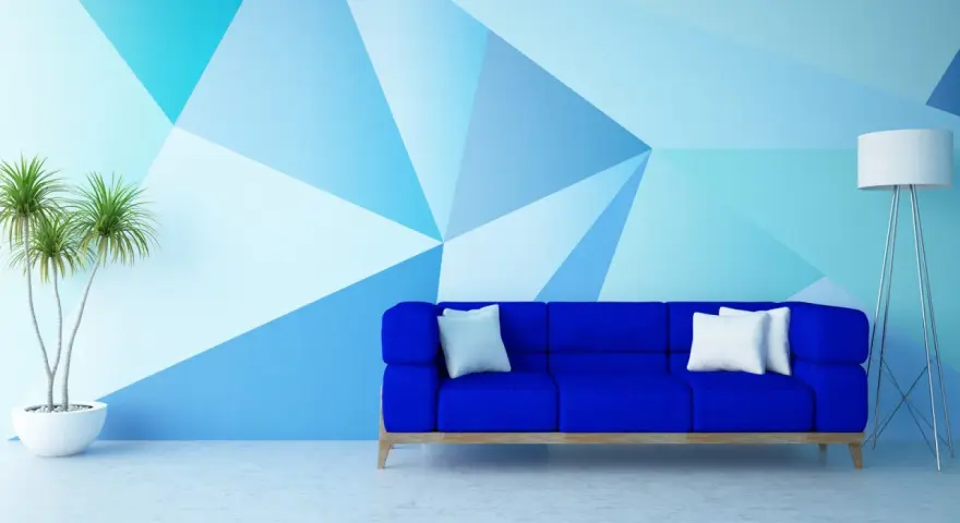 Nowoczesny salon z niebieską kanapą i geometrycznymi wzorami na ścianie malowanymi farbą.