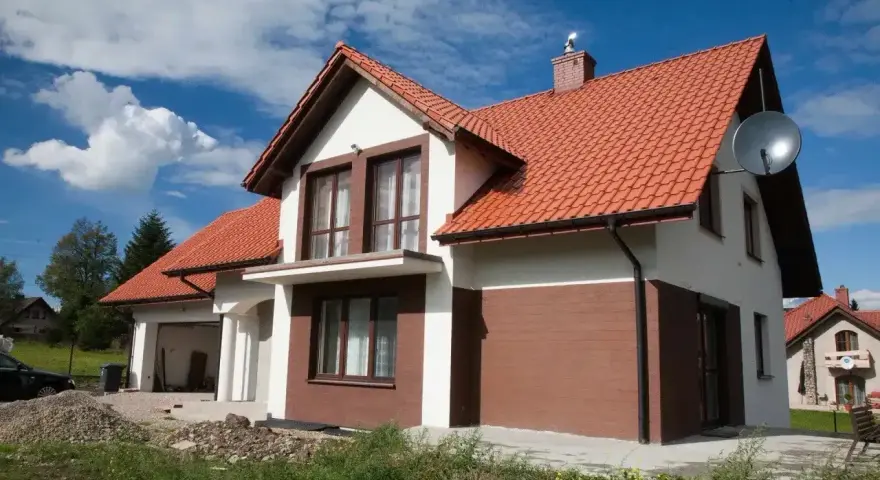 Jaki kolor elewacji do czerwonego dachu? Biała elewacja z brązowymi akcentami, jak na tym domu, wygląda stylowo.